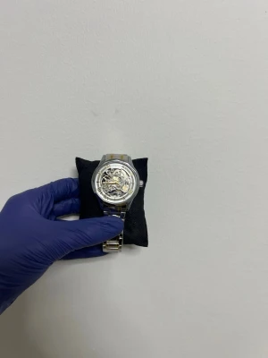 Silverfärgad automatisk klocka - Stilren automatisk klocka från Liuolingongjue med silverfärgat metallarmband och genomskinlig urtavla som visar det mekaniska urverket. Romerska siffror i guld runt urtavlan och detaljer i både silver och guld ger en lyxig känsla. Helt ny aldrig använt den snabb leverans 