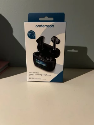 Andersson trådlösa hörlurar TWS-D2500 oöppnad - Oöppnad. Snygga svarta true wireless hörlurar från Andersson med brusreducering och laddningsetui med LCD-display. Hörlurarna har touchkontroll, mikrofon och lång batteritid. Perfekta för musik, samtal och gaming. Levereras med olika storlekar på öronproppar. 