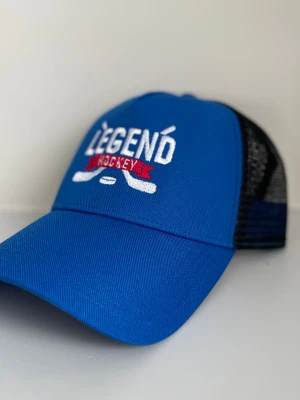 Blå Legend Hockey keps - Snygg blå keps från Legend Hockey med vit brodyr framtill och röd detalj. Framsidan är i tyg och baksidan har svart mesh för extra ventilation. Klassisk böjd skärm och justerbar passform bak. Perfekt för dig som älskar hockey stuket.