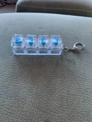Fidget toy keyboard - Keyboard fidget toy med 4 klickbara tangenter som ger en tillfredsställande skrivkänsla. Perfekt för att minska stress och förbättra fokus. Transparent design med blå tangenter och praktisk nyckelring – enkel att ta med överallt.  🚚 Snabb leverans 💬 Tar bud (max 40 kr)