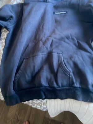 Mörkblå hoodie från Peak Performance - Snygg mörkblå hoodie från Peak Performance med klassisk känguruficka och liten logotyp på bröstet. Hoodien har ribbade muddar vid ärmslut och nederkant samt en stor huva. Perfekt för en avslappnad och sportig stil.