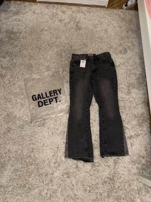 Svarta jeans från Gallery Dept. - Säljer ett par svarta jeans från Gallery Dept. med raka ben och klassisk femficksdesign. Jeansen har en tvättad look och tydliga sömmar, samt etiketter och taggar kvar. Perfekta för dig som gillar streetwear och unik stil.