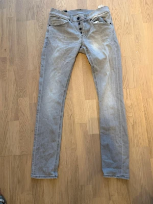 Gråa slim fit jeans med knappar - Snygga gråa slim fit jeans med knappgylf och fem fickor. Jeansen har raka ben och klassisk passform. Materialet är denim i bomull och de har diskreta sömmar. Perfekta för en avslappnad stil.