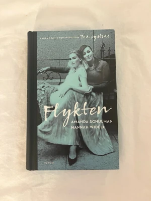 Flykten av Schulman & Widell💞📖 - Romanen 'Flykten' av Amanda Schulman och Hannah Widell är en del av trilogin Trä systrar. Omslaget är svartvitt med två kvinnor i centrum och boken har hårda pärmar. En berättelse om systrar, relationer och att hitta sig själv. 💞📚