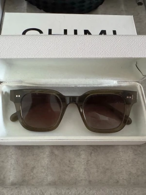 Gröna fyrkantiga solglasögon Chimi 04 - Snygga solglasögon från Chimi med breda, fyrkantiga bågar i mörk grönt transparent material. Glasen är tonade och ger en cool retrovibe. Perfekta för att lyfta vilken outfit som helst. Modell 04❤️