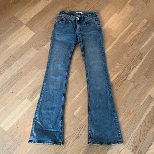 Lågmidjade jeans  - Snygga blå jeans från Gina med klassisk bootcut-passform. Jeansen har fem fickor, normal midja och är tillverkade i slitstarkt denim. Perfekta för dig som gillar en retro vibe och vill ha ett par jeans med lite vidare ben nertill. Lite slitet längst ner.