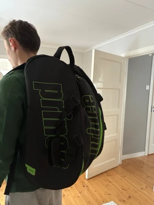Padelväska från Prince - Stor och rymlig padelväska från Prince! Superfin och används extremt lite. Den har ett stort mitten fack där man får plats med allt från kläder, skor osv. Två yttre fack där ett av de är isolerat för värme för padelracken och ett fack för generell användning. En hel och komplett padelväska. 
