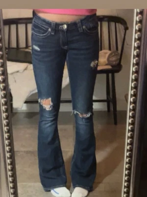 Blå bootcut jeans med slitningar från ginatricot TALL - Snygga blå bootcut jeans med slitningar och ljusa tvättade detaljer från ginatricot TALL. Jeansen har vita kontrastsömmar och broderade bakfickor. Klassisk femficksmodell och låg midja. Perfekta för en avslappnad och trendig look. Har defekter vid hälarna kan ses på sista bilderna. Nypris 399.