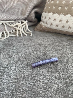 Lila hårklämma med pärlemorskimrande yta Vintage! - Säljer en snygg lila hårklämma i avlång form med pärlemorskimrande yta. Klämman är vintage, har metallspänne på baksidan och passar perfekt för att hålla håret på plats. Enkel men trendig accessoar som ger en färgklick till din look.