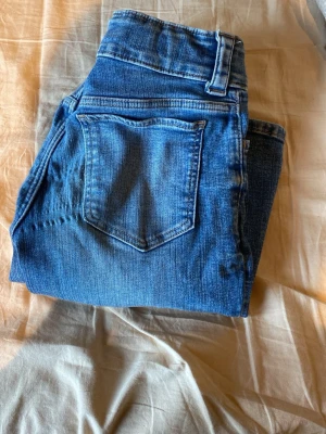 Blå bootcut jeans - Säljer ett par blå bootcut jeans med klassisk denimtvätt. Från hm Jeansen har låg och justerbar midja. Passar mig som är 169