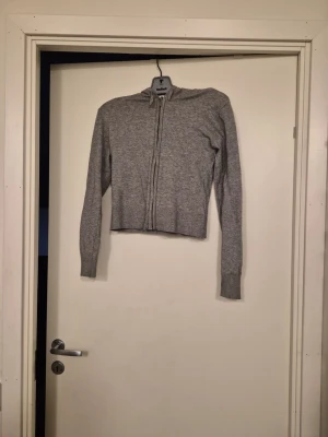 Grå hoodie med dragkedja - En enkel och stilren grå hoodie med dragkedja framtill och långa ärmar. Hoodien har en klassisk huva och är tillverkad i ett mjukt stickat material som känns skönt mot huden. Passar perfekt till ett avslappnat streetwear-utseende. Storleken 158/164