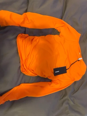 Orange långärmad topp från Weekday - Snygg orange långärmad topp från Weekday med scrunch på sidorna . Tillverkad i mjukt material som känns skönt mot 