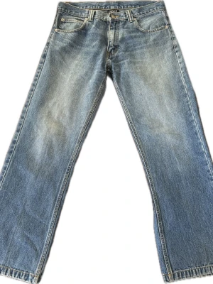 Blåa wide leg bootcut jeans från G.O.F.F - Säljer ett par blåa wide leg/bootcut jeans från  G.O.F.F med klassisk femficksdesign och ljus tvätt. Jeansen har låg/midrise midja och raka, vida ben för en avslappnad och trendig look. Tillverkade i slitstark denim som ger en skön vintagekänsla. Produktionsår: 2000-talet. Innerbenslängd: 72 cm. Midja: 41 cm