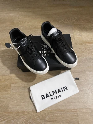 Svarta  sneakers med vit sula - Stilrena svarta sneakers med vit tjock sula och svarta skosnören. Klassisk låg modell i slätt läder med diskret på plösen och hälen. Perfekta för dig som gillar exklusiv och clean streetstyle.