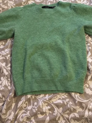 Grön stickad tröja med puffärm - Mysig grön stickad tröja med rund hals och puffärm. Tröjan har ribbstickade muddar vid ärmslut och nederkant, vilket ger en snygg passform. Perfekt för dig som gillar en enkel men trendig look. Storlek M