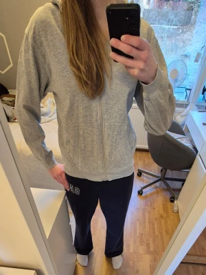 Grå zip hoodie med huva - En klassisk grå zip hoodie med huva och fickor framtill. Hoodien har dragkedja hela vägen och ribbade muddar vid ärmslut och nederkant. Perfekt för chill dagar eller när du vill ha en enkel och stilren look. Materialet känns mjukt och skönt 🌸 skriv för frågor 💕