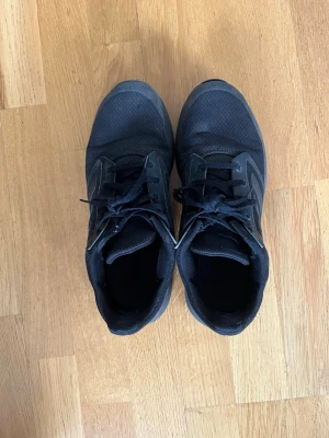 Svarta sneakers med mesh och snörning - Snygga helsvarta sneakers med ovandel i mesh och syntetmaterial. Skorna har klassisk snörning och låg profil som passar till många olika stilar. Perfekta för dig som gillar en clean och sportig look.