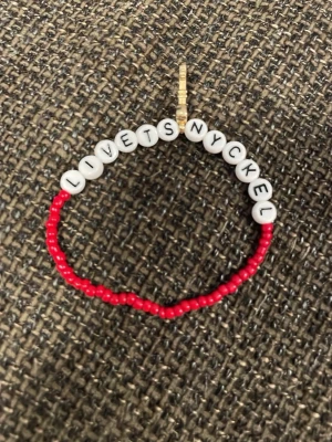 Armband med textpärlor 'LIVETS NYCKEL' - Unikt armband med vita bokstavspärlor som bildar texten 'LIVETS NYCKEL' och små röda pärlor runt om. Perfekt accessoar för dig som vill ha något personligt och färgglatt. Elastiskt band för enkel användning.