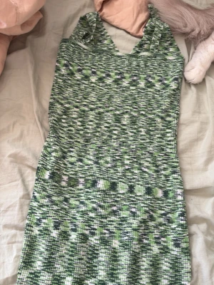 Grön mönstrad kort klänning - Säljer en grön och vit mönstrad kort klänning med smala axelband och v-ringning. Klänningen har ett unikt, nästan pixeligt mönster och är figurnära i modellen. Perfekt för dig som vill sticka ut lite extra.