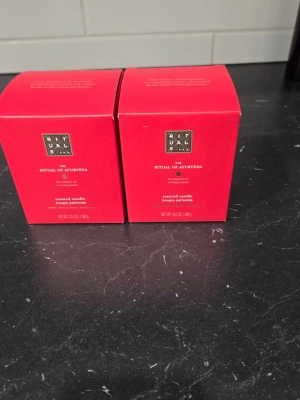 Rituals The Ritual of Ayurveda doftljus 290g x2 - Två doftljus från Rituals, serien The Ritual of Ayurveda 290g. Ljusen kommer i mörkbruna glasbehållare med räfflad yta och guldfärgad etikett. Förpackningarna är röda och stilrena. Perfekt för att skapa en mysig och avslappnad atmosfär hemma.