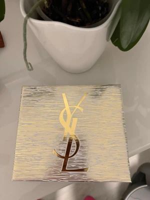 YSL Black Opium parfymset - Snyggt parfymset från Yves Saint Laurent med Black Opium-doften. Setet innehåller en svart och rosa parfymflaska samt en matchande doftpenna. Förpackningen är elegant i guld och vitt med YSL-loggan i metallic. Perfekt present till någon som älskar lyxiga dofter.