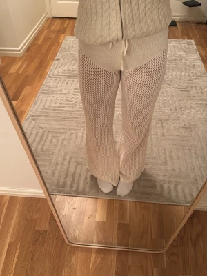 Beige virkade leggings med dragsko - Säljer ett par beige virkade leggings med vida ben och hög midja. De har ett snyggt hålmönster och justerbar midja med dragsko. Perfekta för en chill och trendig look. Materialet är mjukt och stretchigt, troligtvis bomull eller bomullsblandning.Perfekta till stranden 