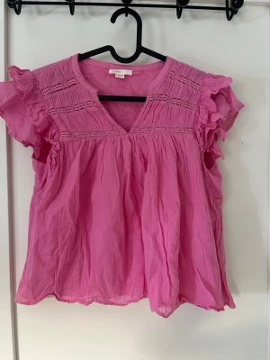 Rosa volangblus med v-ringning - Söt rosa blus med volangärmar och v-ringning. Blusen har dekorativa sömmar upptill och är tillverkad i ett lätt, luftigt material. Den är ifrån Gina tricot och i storlek 158/164 Anvädn få antal gånger.