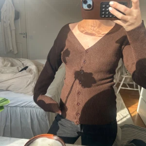 Brun ribbad kofta med v-ringning - Brun ribbad kofta med djup v-ringning och knappar som man kan öppna!  