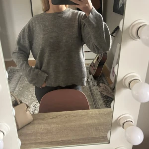 Grå stickad tröja. - Säljer en grå stickad tröja ifrån Mango, jätte fin och jätte använd. Bra sick bort seende från ett litet hål i armhålan. Tänker att det är lätt att laga💕En liten L i storleken