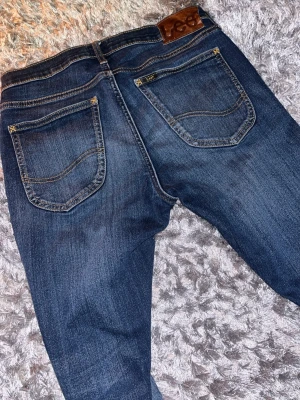 Mörkblå jeans  Lee - Snygga mörkblå jeans från Lee med klassisk femficksdesign och guldfärgade detaljer. Jeansen har en något tvättad look och är tillverkade i slitstark denim. Perfekta för dig som gillar en tidlös och cool stil. Pris går att diskutera!