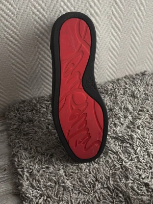 Svarta sneakers från Christian Louboutin - Snygga svarta sneakers från Christian Louboutin med klassisk röd sula och diskret logga på sidan. Skorna är låga och har ovandel i mocka med svarta skosnören. Perfekta för dig som vill ha en exklusiv och stilren look. Släng iväg ett PM ifall du är intresserad. Jag skickar varan så fort som möjligt☺️ Ett annat pris skulle även kunna diskuteras då priset inte är hugget i sten ännu🫡