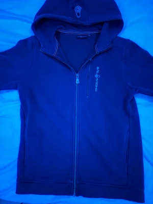 Marinblå hoodie från Sail Racing - Säljer en blå sailracing hoodie i bra skick.