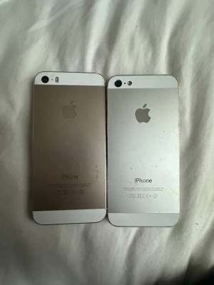 Två iPhone 5/5s i silver och guld - Säljer två iPhones, en i silver och en i guld. Båda har klassisk rektangulär form med aluminiumskal och vit framsida. En har Touch ID-knapp, den andra vanlig hemknapp. Perfekt för dig som gillar smidiga och stilrena mobiler från Apple. En mobil upplåst en med iTunes lås 