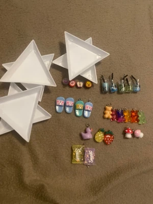 Färgglada smyckesberlocker mix - Säljer ett set med söta och färgglada smyckesberlocker i olika former som nallar, jordgubbar, svamp, dryckesglas, tofflor och godis. Perfekta att använda till egna smycken eller som dekoration. Materialet är plast och akryl i flera färger som lila, blå, röd, grön och gul.