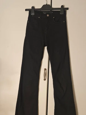 Svarta bootcut jeans midrise - Säljer ett par svarta bootcut jeans med midrisel. Jeansen har utsvängda ben ör gjorda i ganska mjukt stretchigt tyg. 