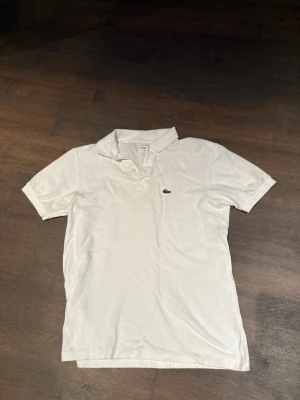 Vit pikétröja från Lacoste - Klassisk vit pikétröja från Lacoste | storlek 16y | hör av er vid frågor |