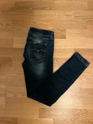 Mörkblå jeans från Replay - Snygga mörkblå skinny jeans från Replay med slitningar och tvättade detaljer. Klassisk femficksmodell med låg midja och smala ben. Perfekta för en avslappnad och trendig look.