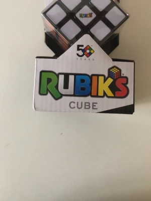Rubiks kub 3x3 jubileumsutgåva - Rubiks kub 3x3 i klassisk design, jubileumsutgåva för 50 år. Kuben har färgerna vit, grön, röd, blå, gul och orange. Perfekt för dig som gillar kluriga pussel och vill utmana hjärnan. Levereras i originalförpackning.