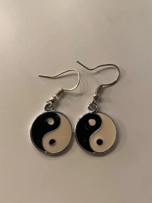 Yin yang örhängen i svart och vitt - Coola örhängen med yin yang-symbol i svart och vitt. Runda hängen i metall med krokfäste, perfekt för dig som gillar en unik och stilren look. Helt oanvända och ej äkta silver 🫶