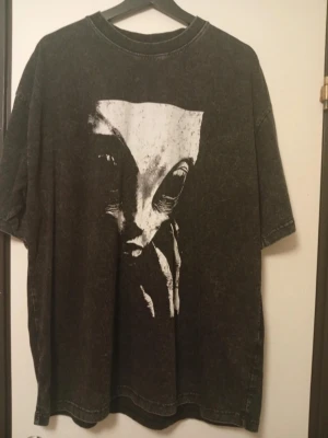 Svart oversized t-shirt med alientryck - Cool svart oversized t-shirt med ett stort vitt tryck av ett alienansikte på framsidan. T-shirten har korta ärmar och en avslappnad passform. Perfekt för dig som gillar unika och lite edgy plagg. T shirt nr 2 är tryck utav Roswell incidenten 1947 i old fashioned retro sci fi vibe. Båda i nyskick. Inte använda.  Köpta på Nerdywave Apparel. Storlek XL