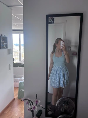 Pernilla Wahlgren kortkjol - En söt Pernilla Wahlgren kortkjol med blått och vitt blommönster. Kjolen har en volangig och luftig passform. Aldrig använd 