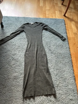 Grå långärmad klänning H&M - Snygg grå långklänning från H&M med lång ärm och rund halsringning. Klänningen är figurnära och har en enkel, stilren design i mjukt stretchigt material. Perfekt för dig som gillar minimalistisk stil.☺️☺️
