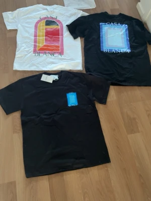 Casa Blanca t-shirts med tryck - Tre snygga t-shirts från Casa Blanca, två svarta och en vit. Alla har coola grafiska tryck på bröstet eller ryggen i färger som blått, rött och gult. Klassisk passform och korta ärmar, perfekta till jeans eller shorts., vit strl M en svart M den andra L, checka min profil!💪🏽💪🏽