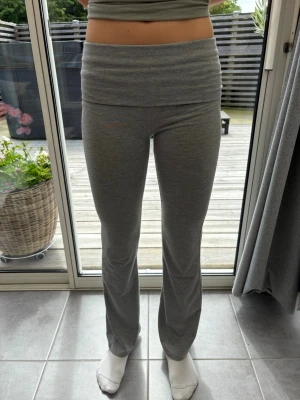 Grå bootcut yoga pants med stjärna - Säljer ett par grå yoga pants med bootcut-modell och låg midja. På baksidan finns en diskret stjärndetalj. Mjukt och stretchigt material som sitter skönt på kroppen. Perfekta för en chill och avslappnad stil.