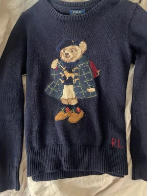 Mörkblå stickad tröja Polo Bear - Säljer min jättefina, trendiga  polo ralph lauren tröja den är i jättebra skick och passar perfekt under dem kyligare dagarna, skriv gärna om ni har några frågor eller är intresserade .