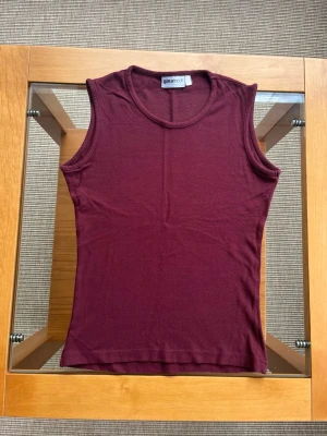 Vinröd ärmlös topp från Gina Tricot - Ärmlös topp i en djup, vinröd nyans. Figurnära passform. Stretchigt material. 