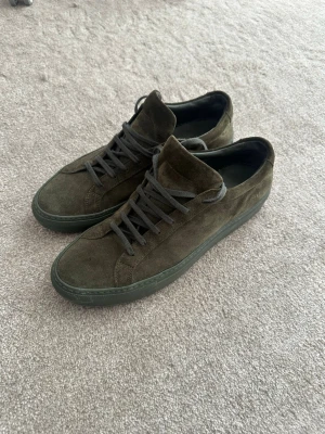 Common projects mörkgröna  - Ett par riktigt feta mörkgröna skor från common projects. Jättefint skick har bara haft på mig de några gånger och de kostar runt 4000kr nya. Perfekt till dig som vill ha ett par feta skor som inte alla andra har!