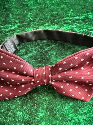 Vinröd fluga med vita prickar - Snygg vinröd fluga från One Way med små vita stjärnformade prickar. Flugan har justerbart svart band och klassisk form. Tillverkad i polyester för en stilren look. Perfekt accessoar för att lyfta din outfit.