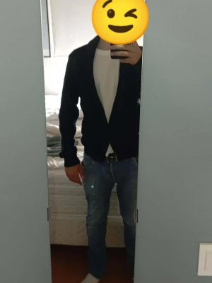 Mörkblå kofta från Dressmann - Säljer en mörkblå stickad kofta från Dressmann med sjalkrage och knäppning framtill. Koftan har en klassisk, avslappnad passform och är tillverkad i ett mjukt, ribbstickat material. Perfekt att slänga över en t-shirt för en clean look.