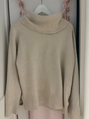 Polotröja med bred krage - Så mysig beige stickad polotröja med bred ribbad krage och ribbade muddar vid ärmslut och nederkant. Tröjan har en avslappnad passform och är perfekt för lager på lager. Materialet känns mjukt och skönt mot huden. Perfekt för sena sommarkvällar💗💗😍